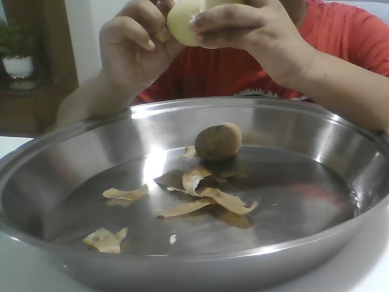 Child practising independent food-preparation skills over a steel bowl, part of a Kikstart occupational therapy daily-living activity